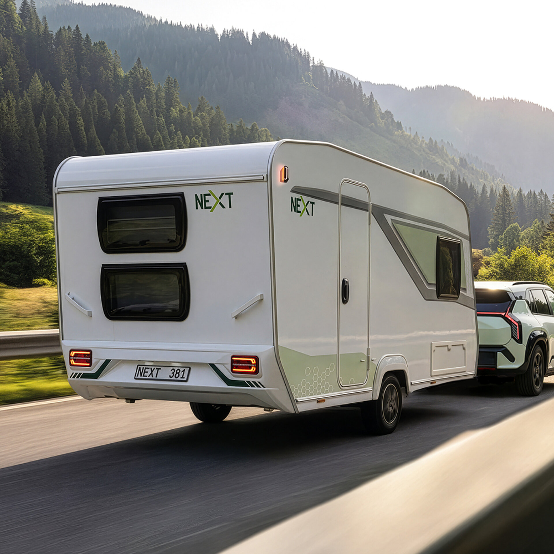 Ein NEXT 381 Caravan wird eine Landstraße entlanggezogen. 