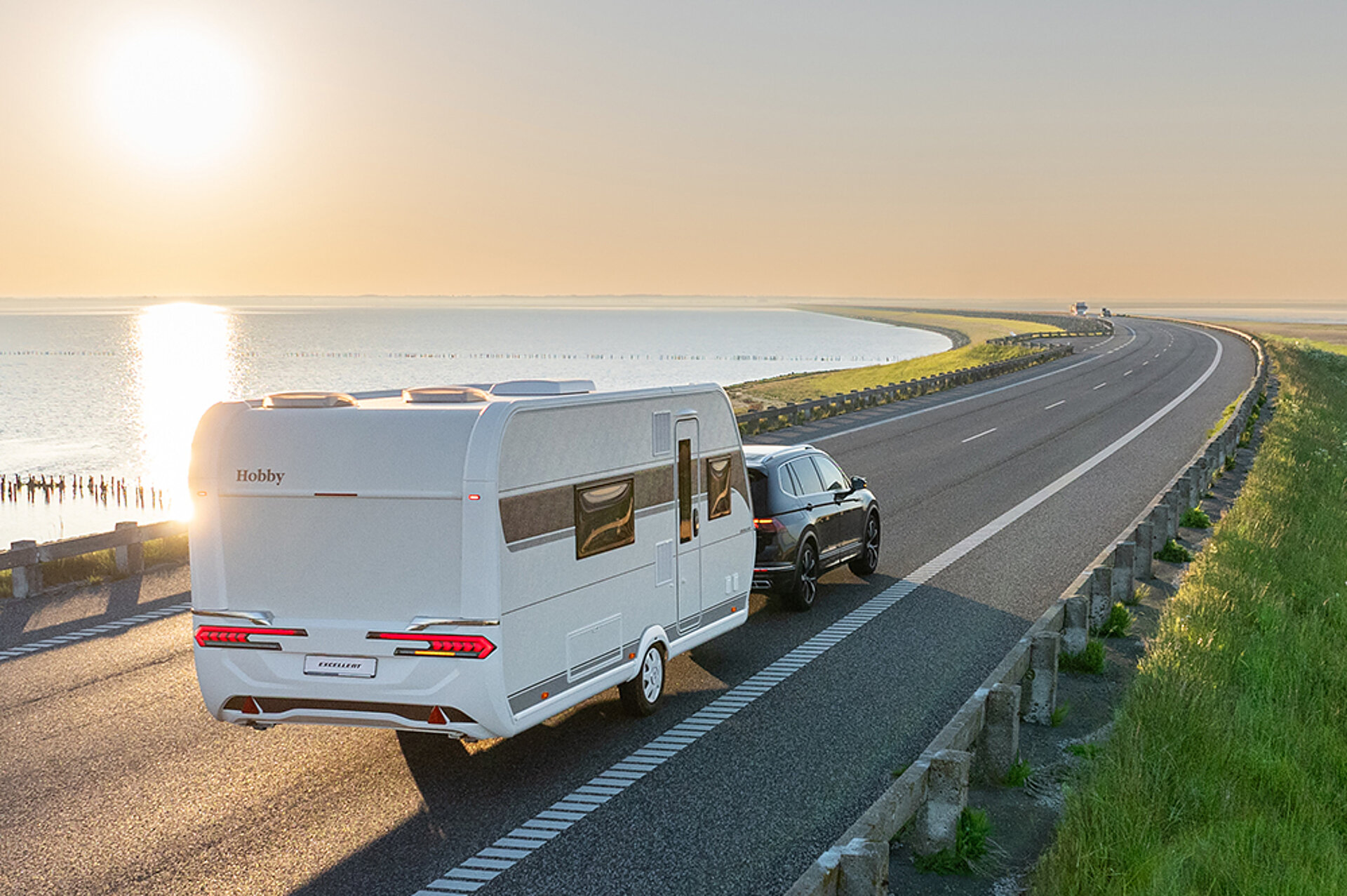 Ein Hobby Caravan wird eine Straße im Gegenlicht entlang gezogen.