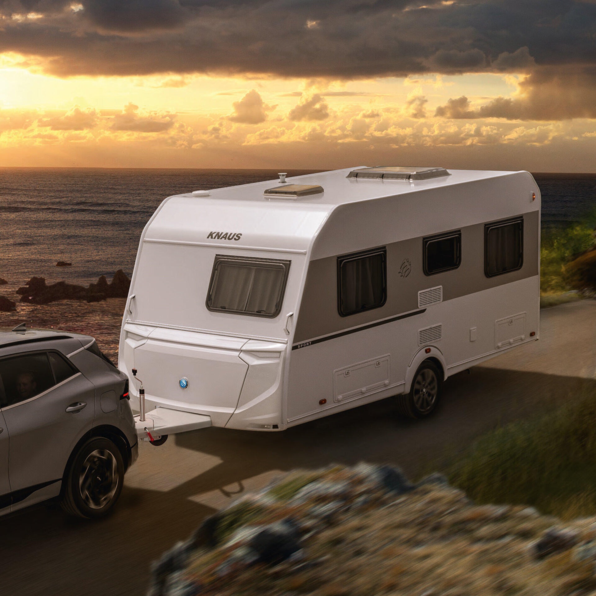 Ein KNAUS SPORT Caravan wird eine Landstraße entlanggezogen.