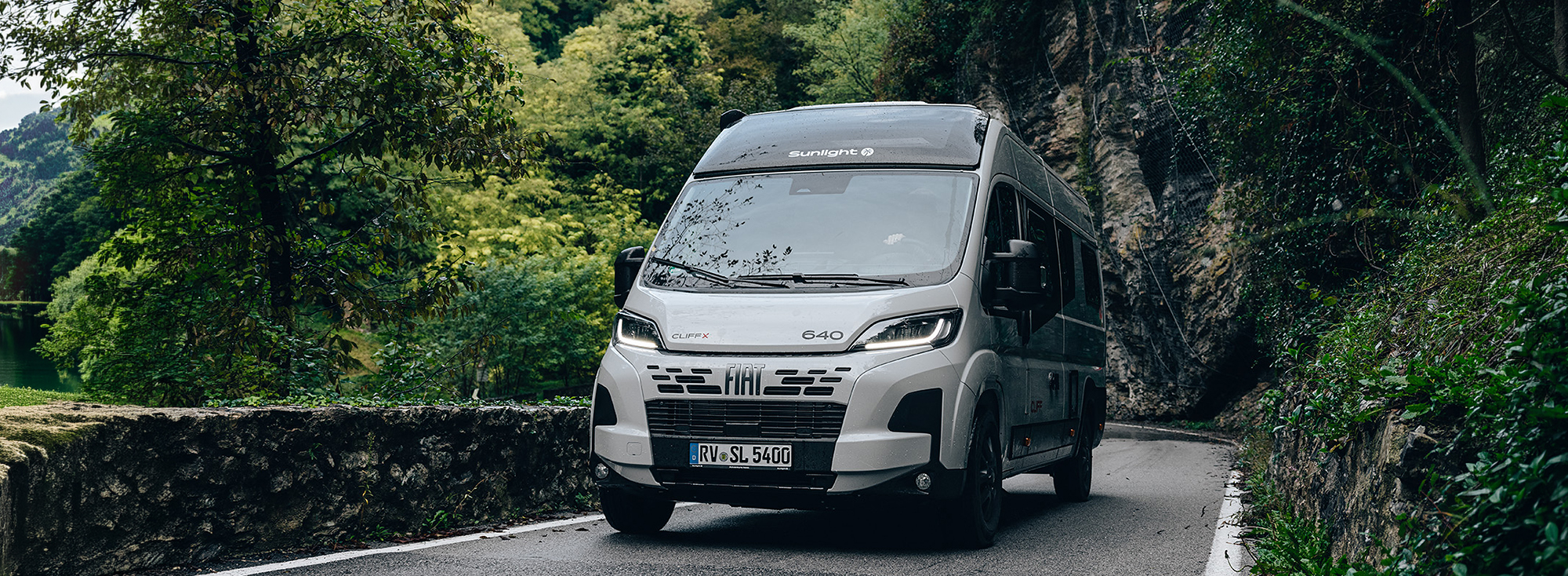 Ein Sunlight Camper Van fährt eine Landstraße entlang.