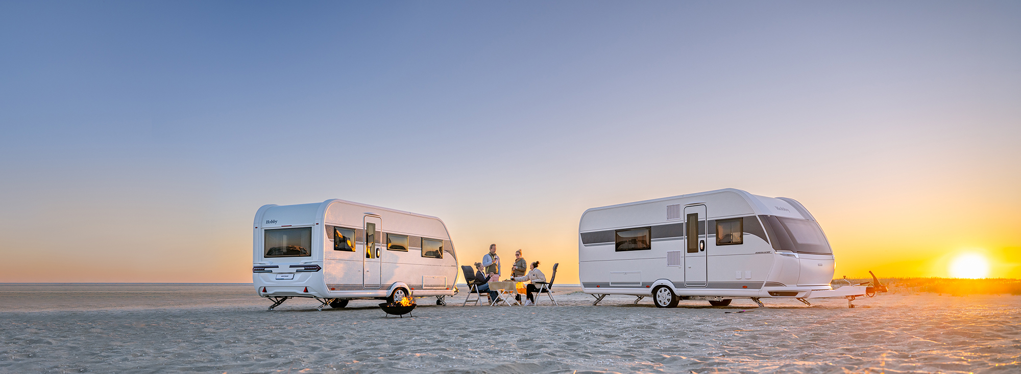 Zwei Hobby Wohnwagen stehen an einem malerischen Strand.